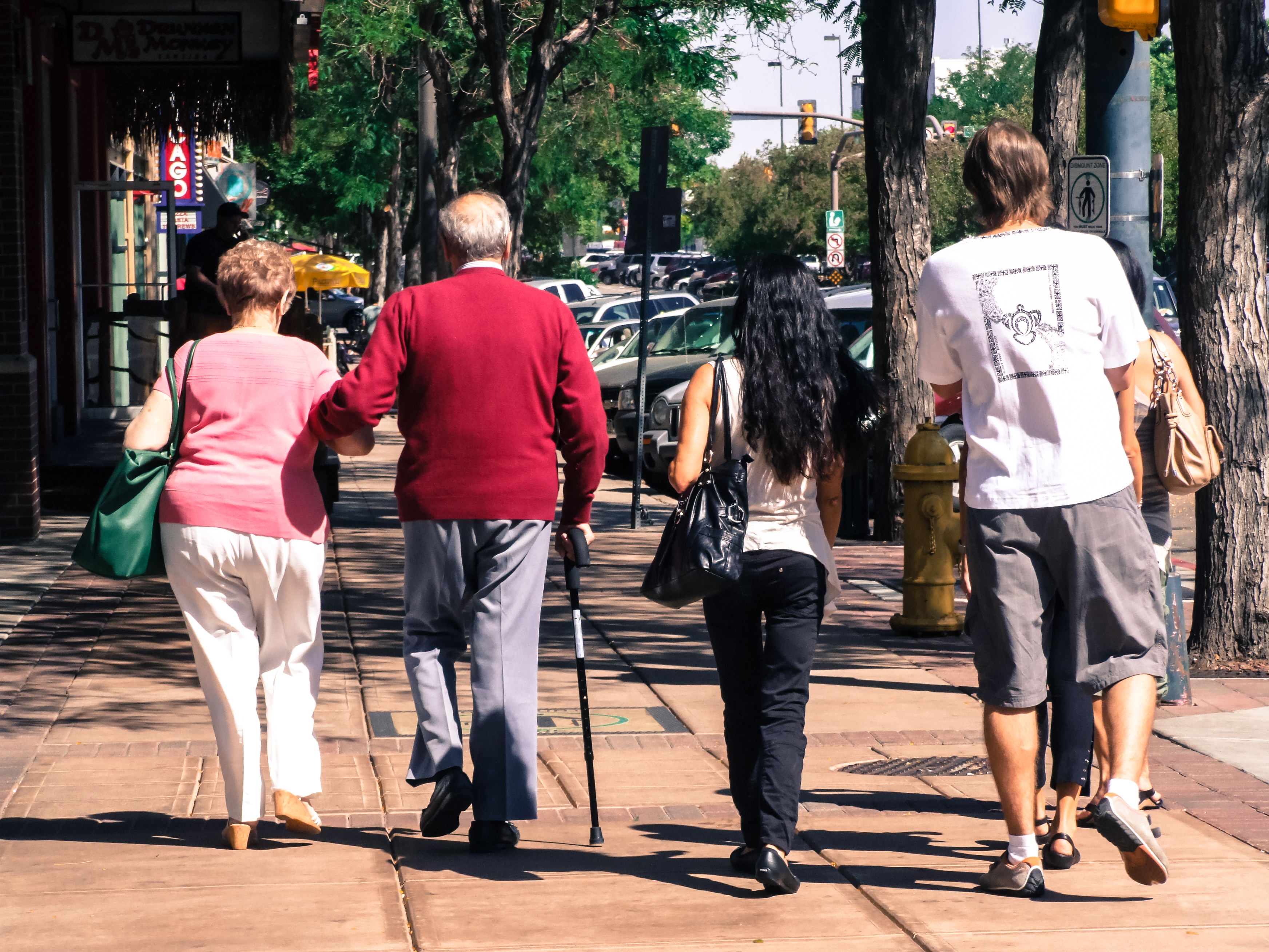 elderly couple walking in the street next to young persons